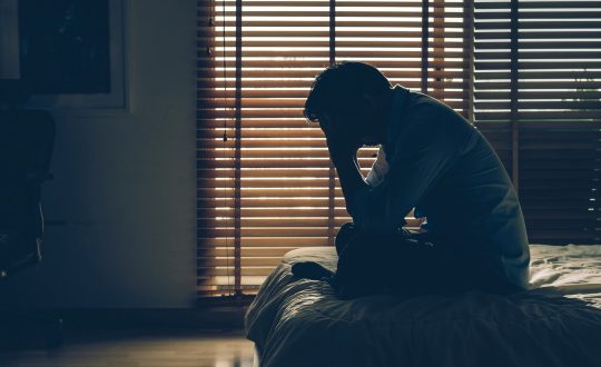 sad-businessman-sitting-head-hands-bed-dark-bedroom